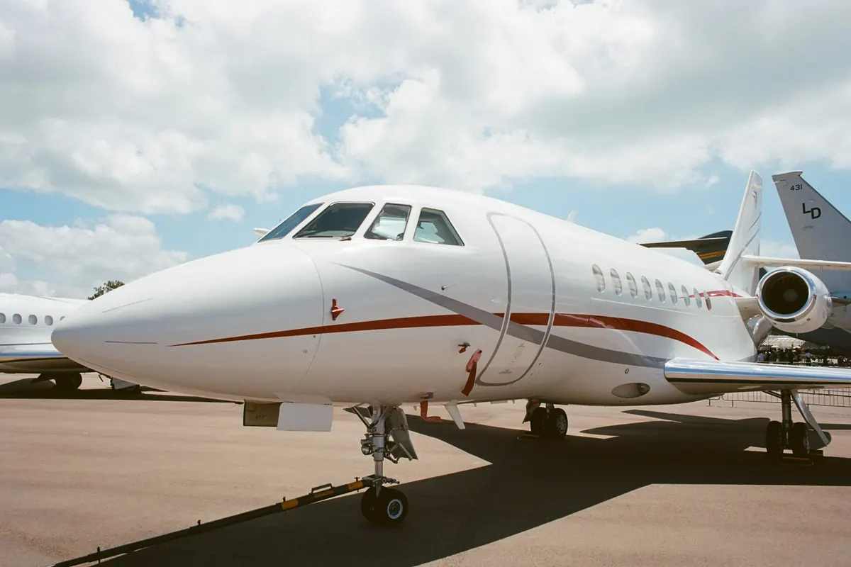 Nose of a white business jet parked on the ramp