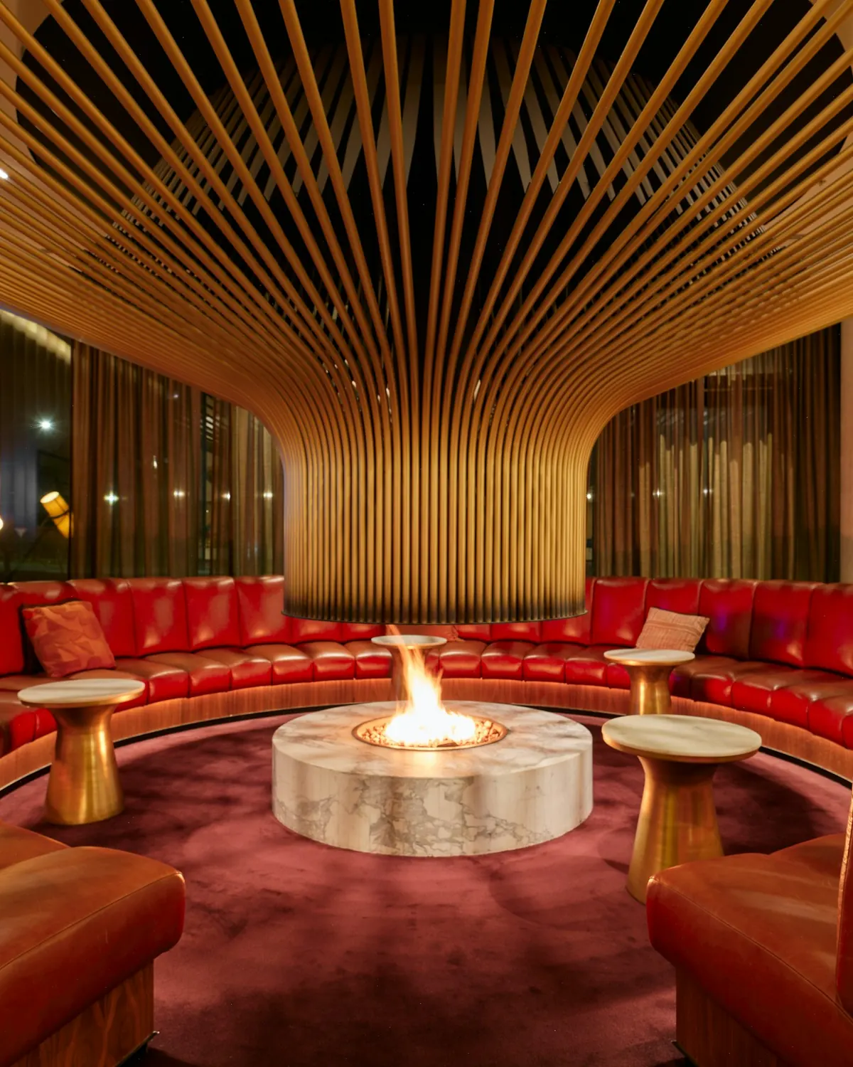 Lounge with red leather banquettes around a lit fire pit